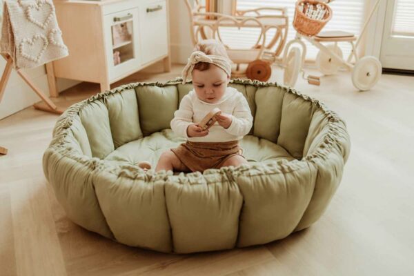 PlayandGo_organic_babymat_Bloom_meadow_green_child_sitting_on_mat_in_kidsroom_raised_edges Play&Go 3u1 Bloom podloga za igru i gnijezdo za bebe - Meadow Green - Image 15