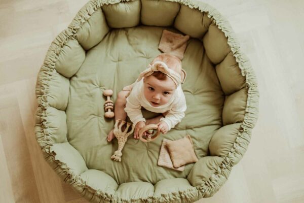 PlayandGo_organic_babymat_Bloom_meadow_green_child_sitting_on_mat_looking_up Play&Go 3u1 Bloom podloga za igru i gnijezdo za bebe - Meadow Green - Image 2