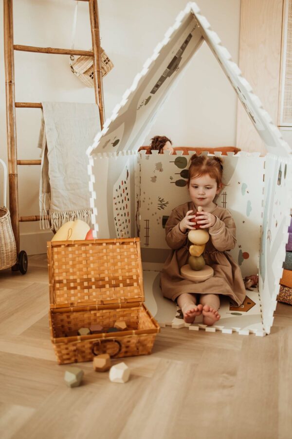 PlayandGo_EEVAA_farm_puzzlemat_made_in_a_playhouse_child_is_sitting_inside_while_playing_with_wooden_toys_wooden_basket Play&Go 3u1 EEVAA dvostrana podloga za igru – Farma (120x180cm) - Image 14