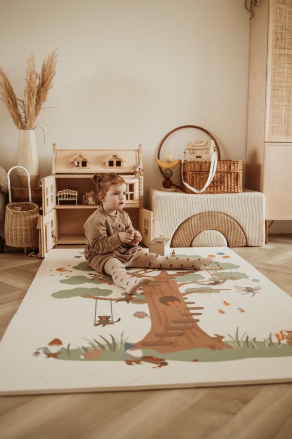 PlayandGo_EEVAA_treehouse_puzzlemat_child_is_sitting_on_the_mat_in_kidsroom_victorian_house_wooden_basket Play&Go 3u1 EEVAA dvostrana podloga za igru – Kućica na drvetu/Zvjezdice (120x180cm) - Image 16