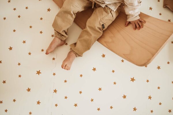 PlayandGo_EEVAA_treehouse_puzzlemat_child_sitting_on_a_wooden_swing_board Play&Go 3u1 EEVAA dvostrana podloga za igru – Kućica na drvetu/Zvjezdice (120x180cm) - Image 9