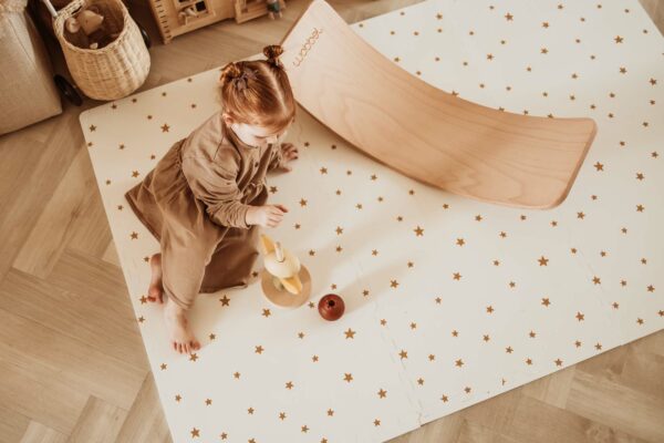 PlayandGo_EEVAA_treehouse_puzzlemat_child_sitting_on_the_mat_with_stars_print_wooden_swing_board_wooden_toys Play&Go 3u1 EEVAA dvostrana podloga za igru – Kućica na drvetu/Zvjezdice (120x180cm) - Image 6