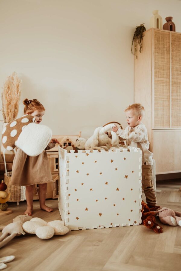 PlayandGo_EEVAA_treehouse_puzzlemat_children_are_cleaning_up_the room_by_putting_the_cuddles-into_the_EEVAA_box_with_stars_print Play&Go 3u1 EEVAA dvostrana podloga za igru – Kućica na drvetu/Zvjezdice (120x180cm) - Image 4